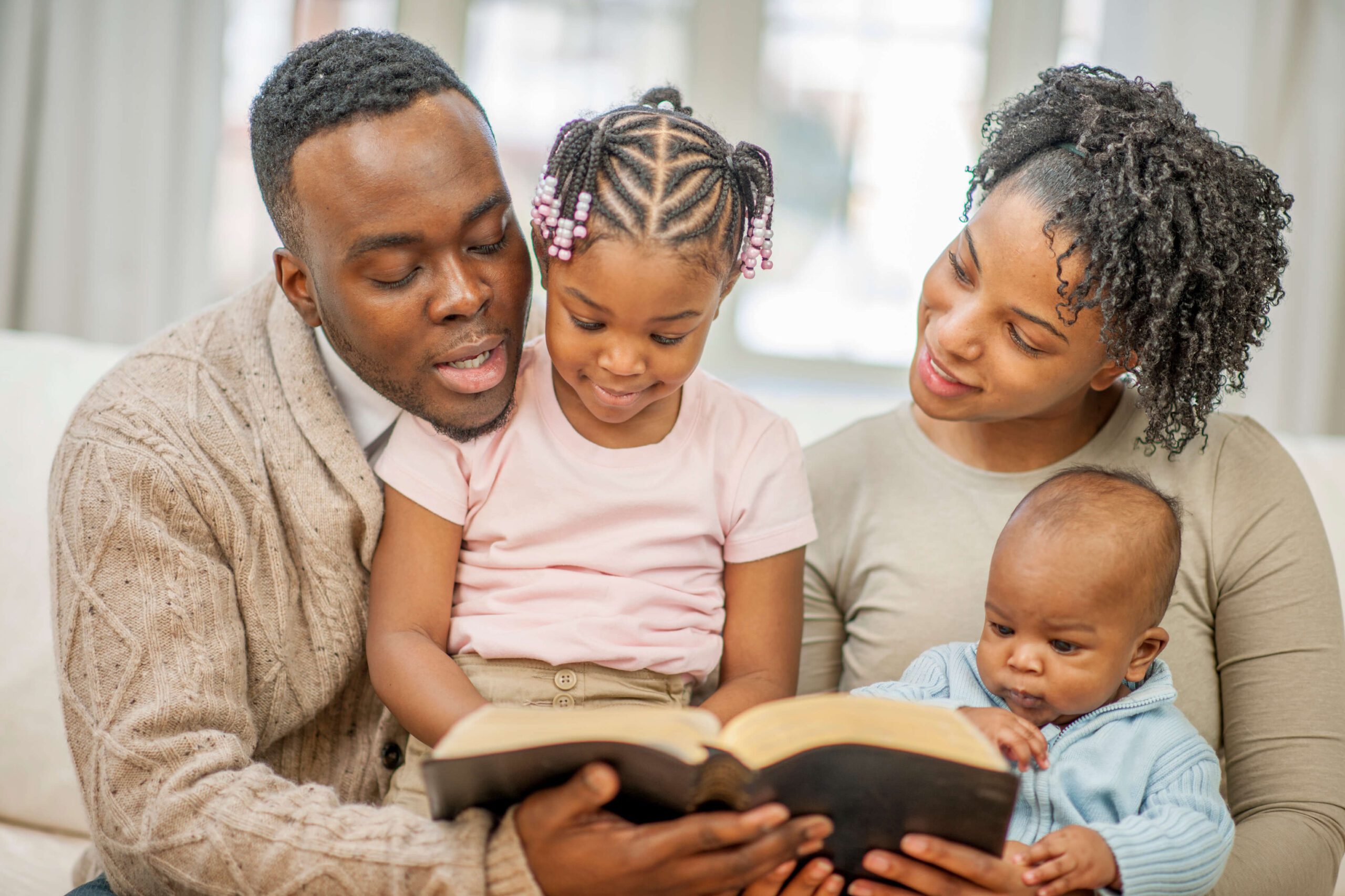 Family Reading The Bible On Living Room